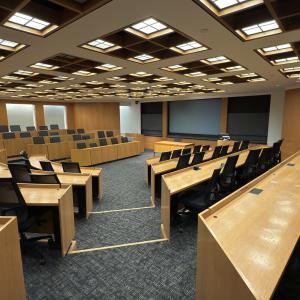 Modern lecture hall with tiered seating and large screens.